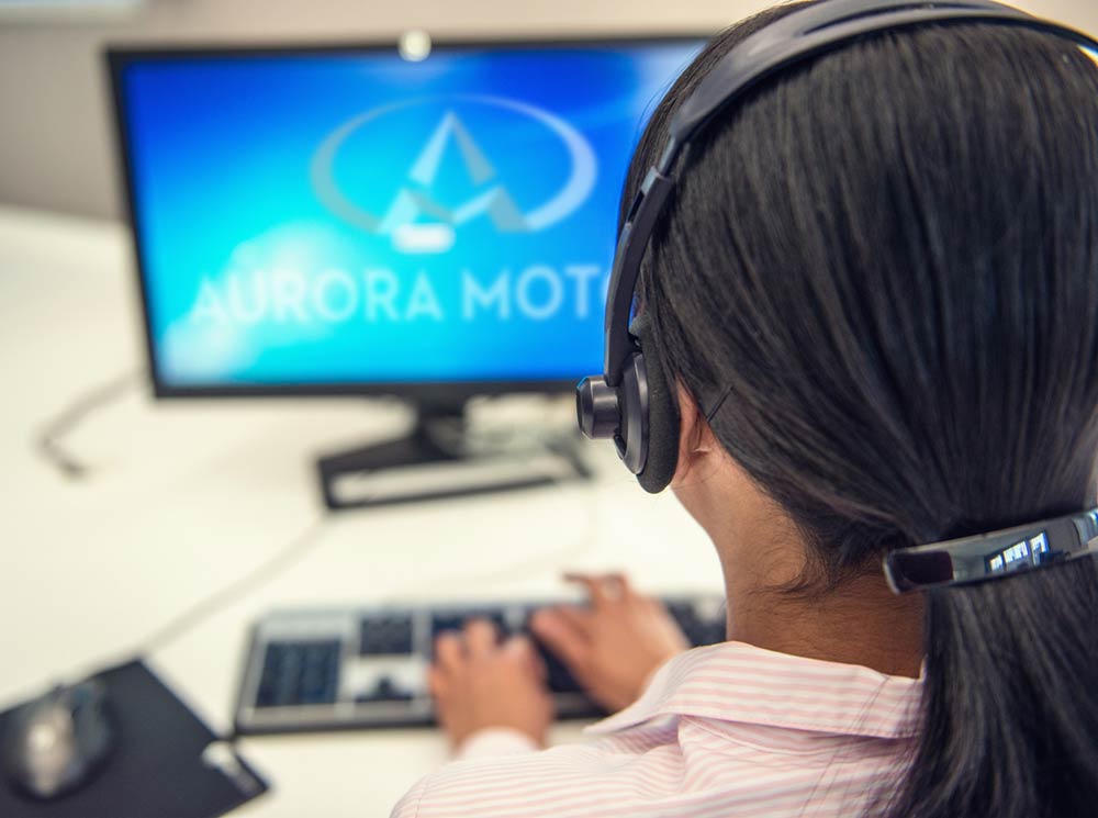 Customer Service Rep in front of a Aurora Motors screen